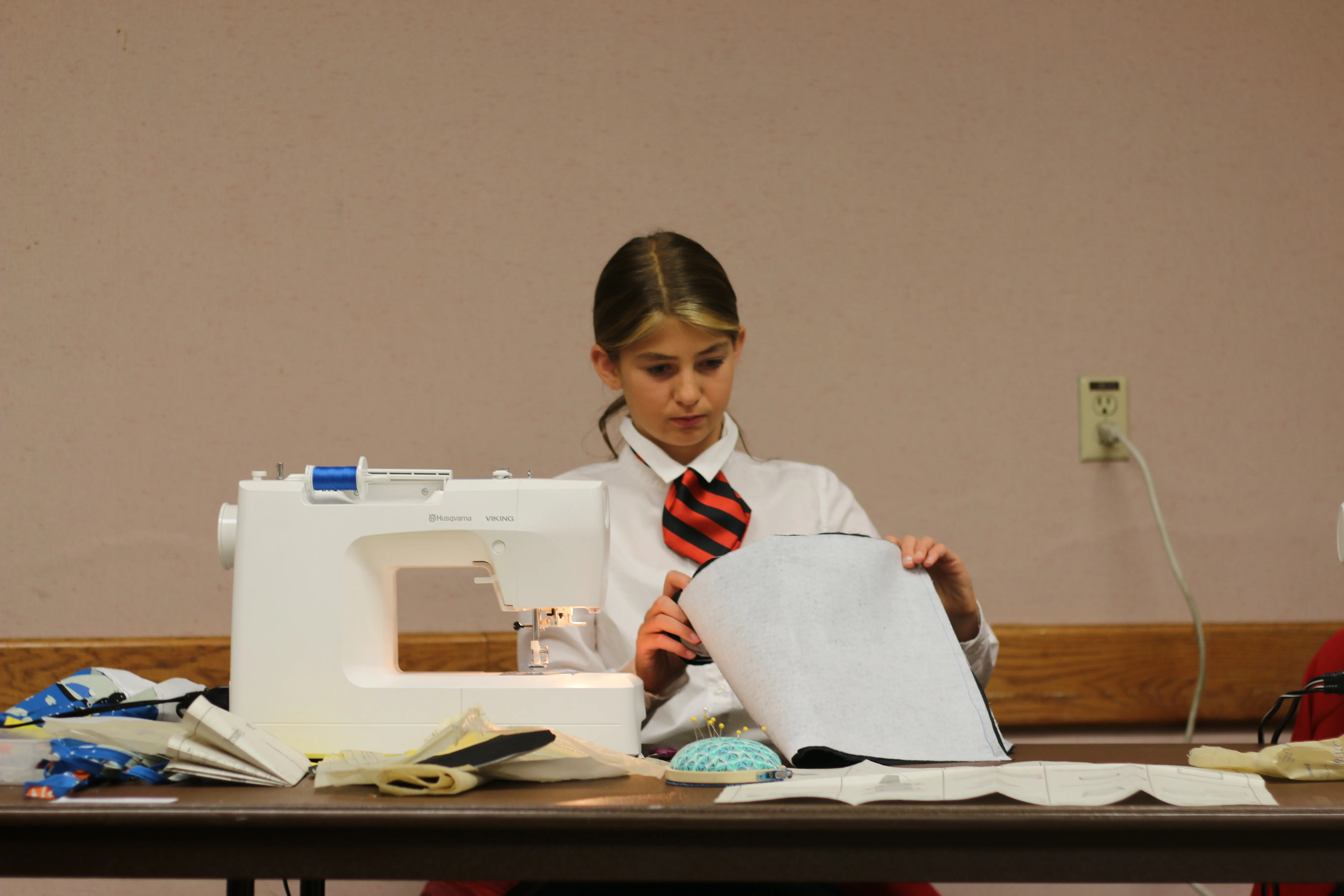 young person in uniform at sewing machine